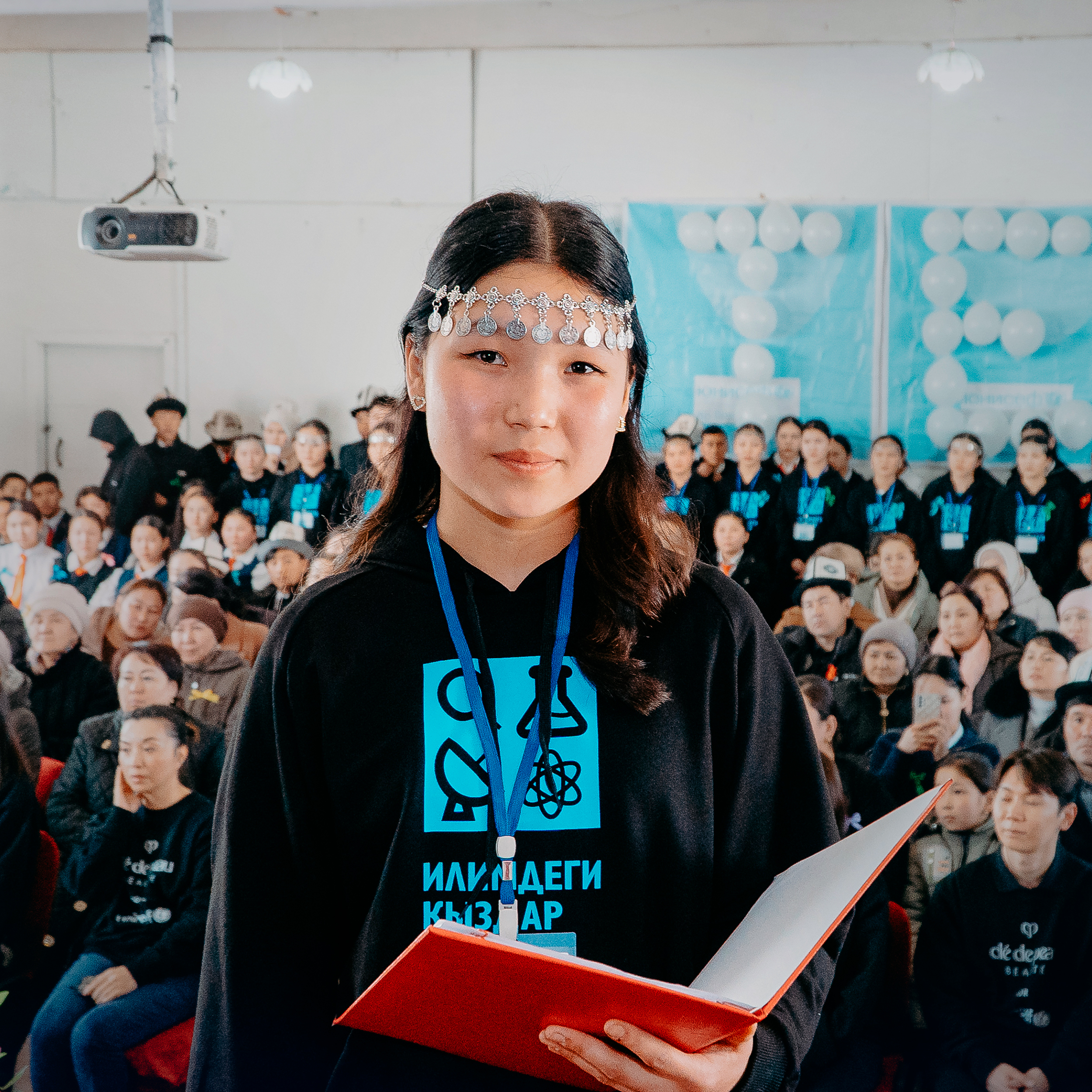 Photo of a girl holding a red notebook in Kyrgyzstan, taken during Cl&eacute; de Peau Beaut&eacute;&rsquo;s 2025 UNICEF partnership visit.