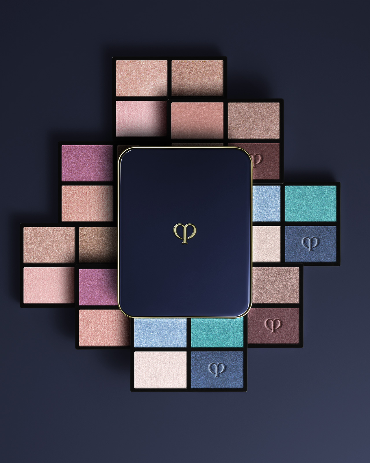 Photo of the EYE COLOR QUAD (REFILL) collection. A blue-black compact case is placed in the center, and refills in beige, purple, and blue tones are arranged in a radial pattern.