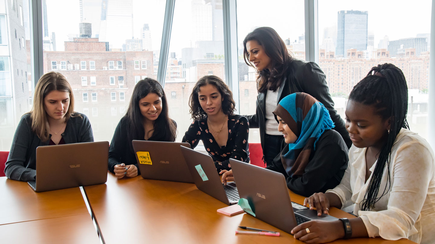 Photo of Reshma Saujani collaborating with five women using a laptop.