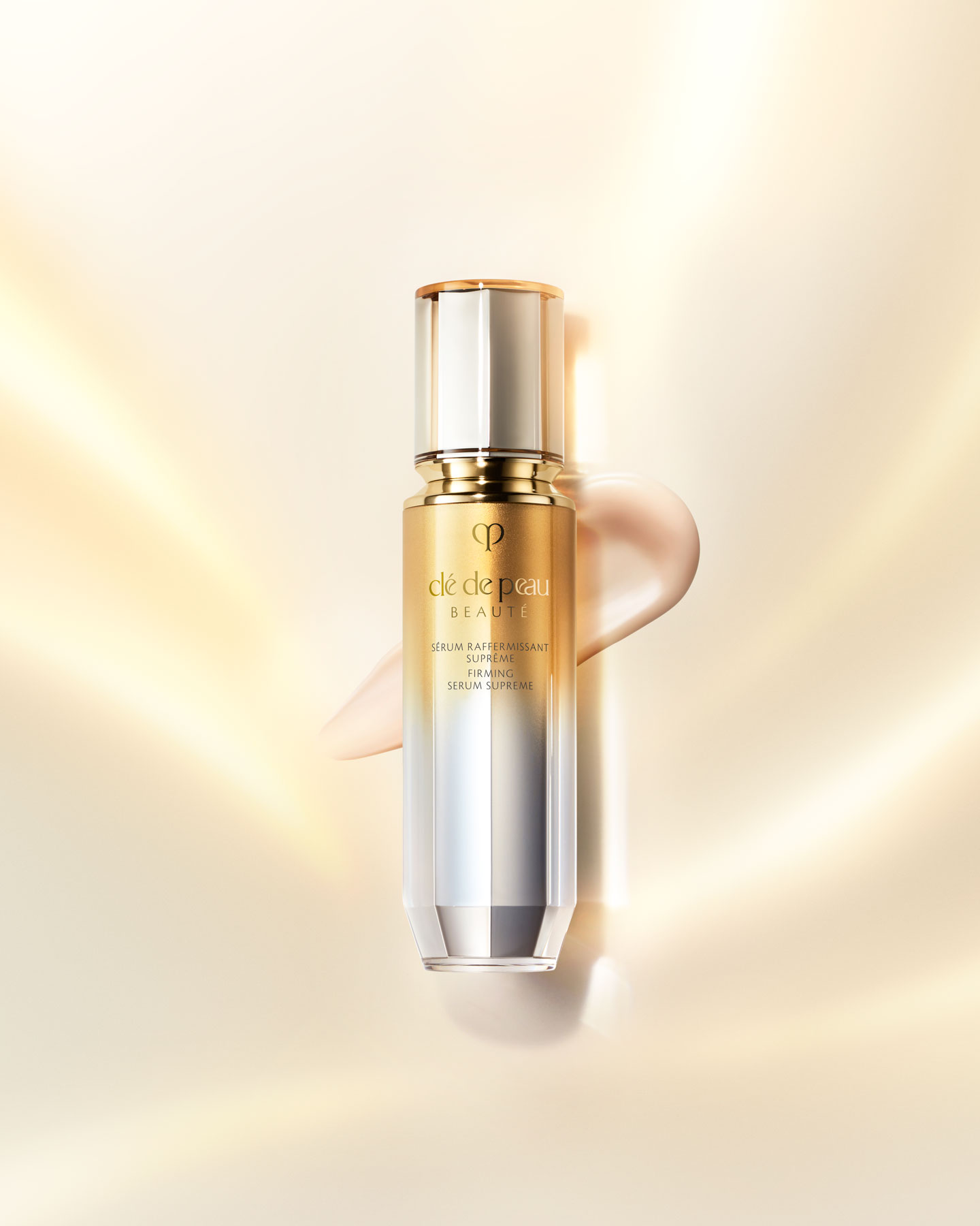 Photo of a FIRMING SERUM SUPREME bottle with a gradient design transitioning from gold at the top to silver at the bottom.