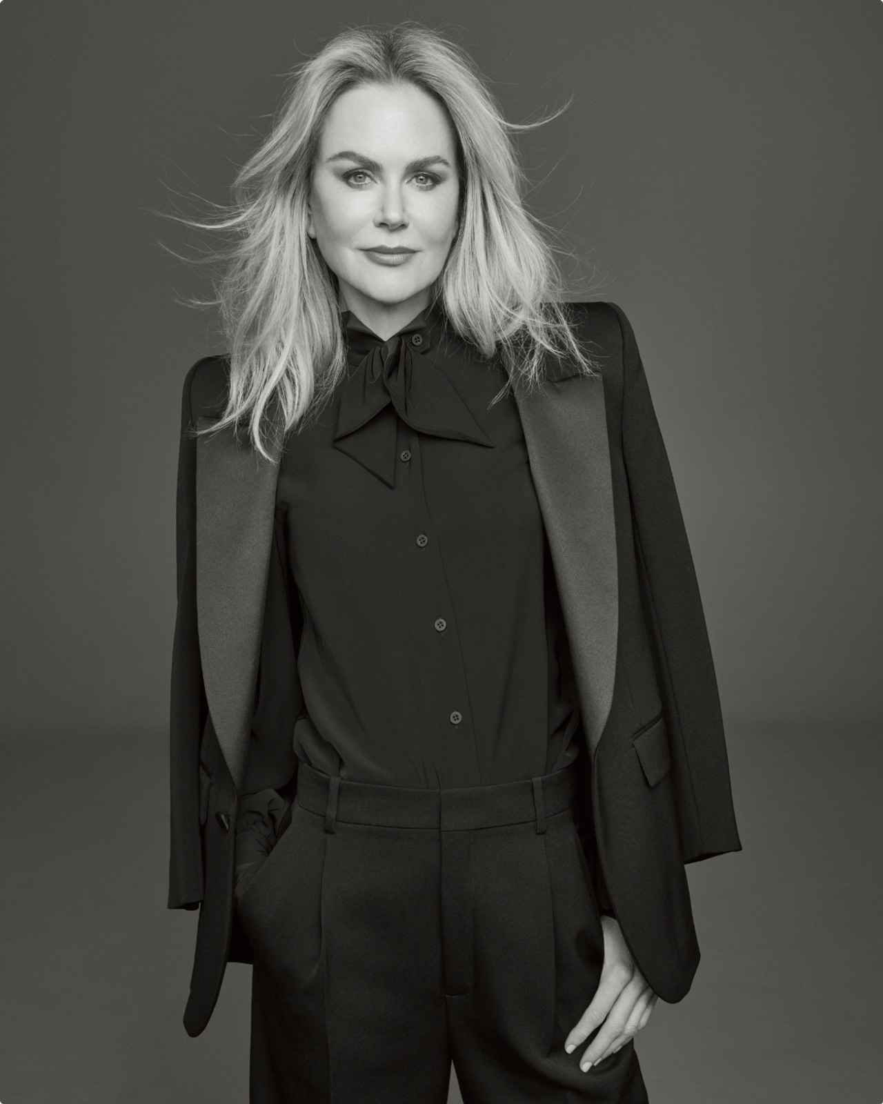 Photo of Cl&eacute; de Peau Beaut&eacute;&rsquo;s new global brand ambassador, Nicole Kidman, wearing a black suit with right hand in pocket, looking directly at the camera in a monochrome image.