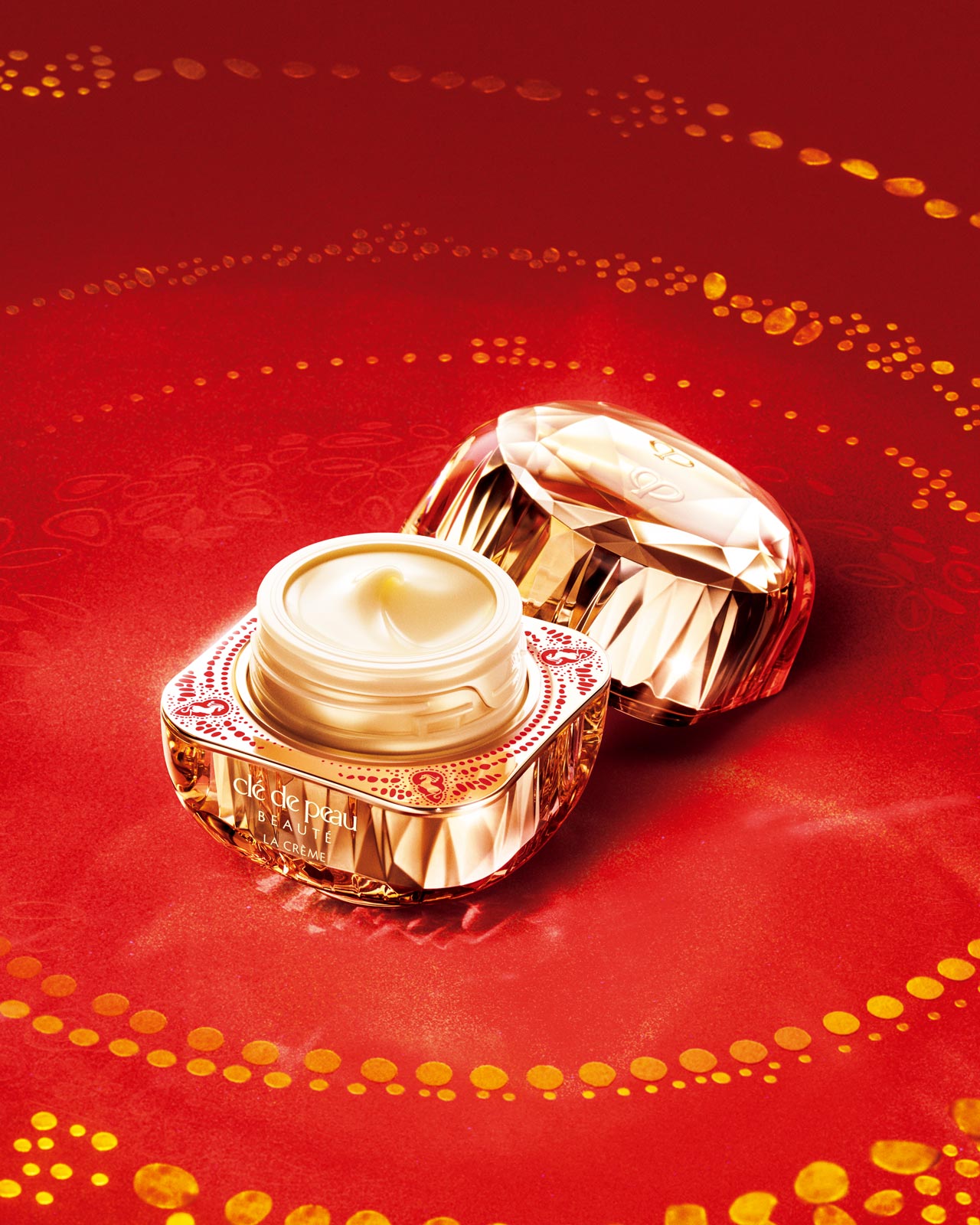 Photo of Cl&eacute; de Peau Beaut&eacute;'s limited-edition LA CR&Egrave;ME for Lunar New Year. The gold jar, decorated with a red and gold horse motif, is open to show the cream inside.