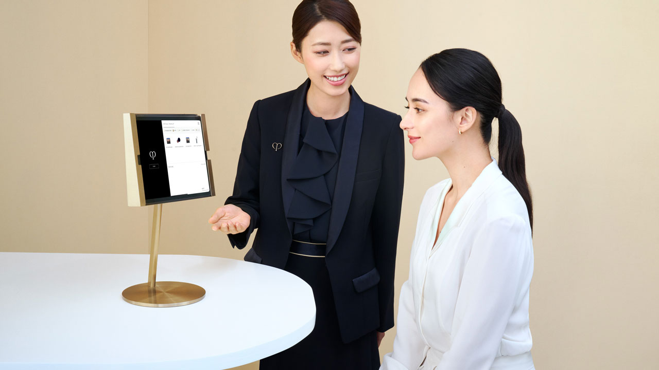 Photo of a personal beauty specialist explaining skin analysis results to a woman while referring to a tablet on the table.