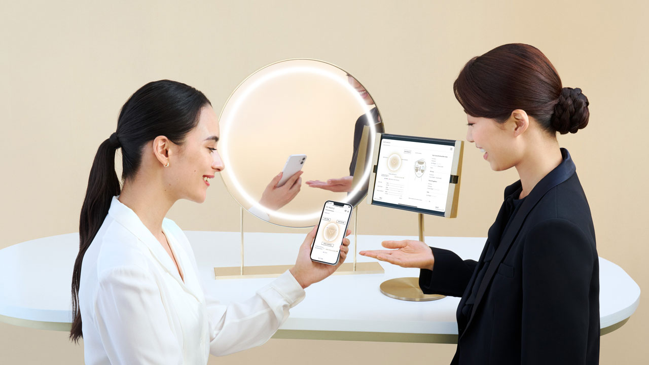 Photo of a personal beauty specialist clearly explaining skincare information to a woman using a smartphone app screen.