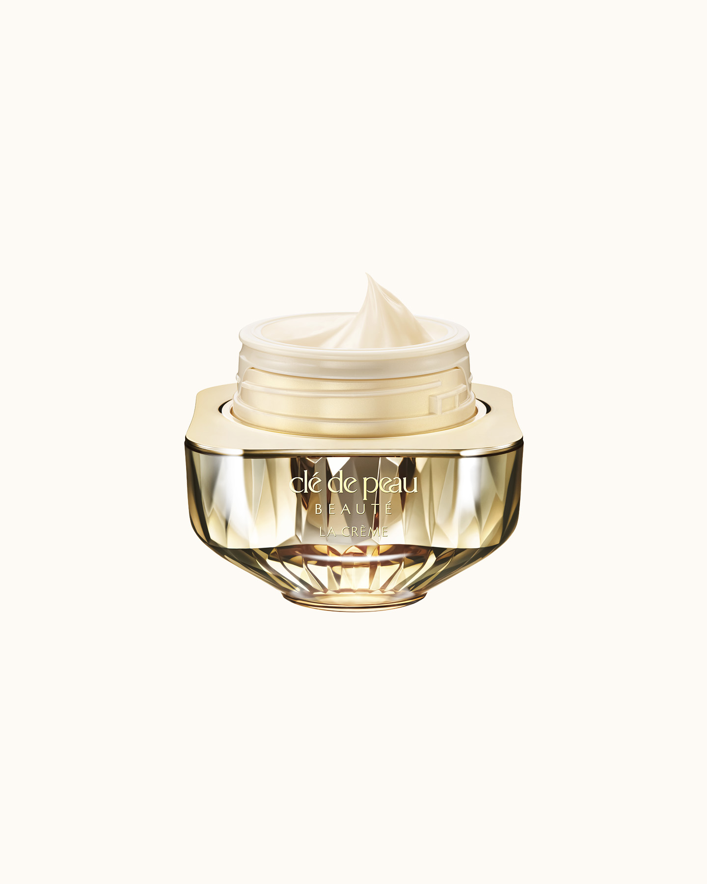 Photo of Cl&eacute; de Peau Beaut&eacute;&rsquo;s high-performance cream &ldquo;La Cr&egrave;me,&rdquo; housed in a jewel-cut, translucent gold container. The lid is open, revealing the smooth cream inside.