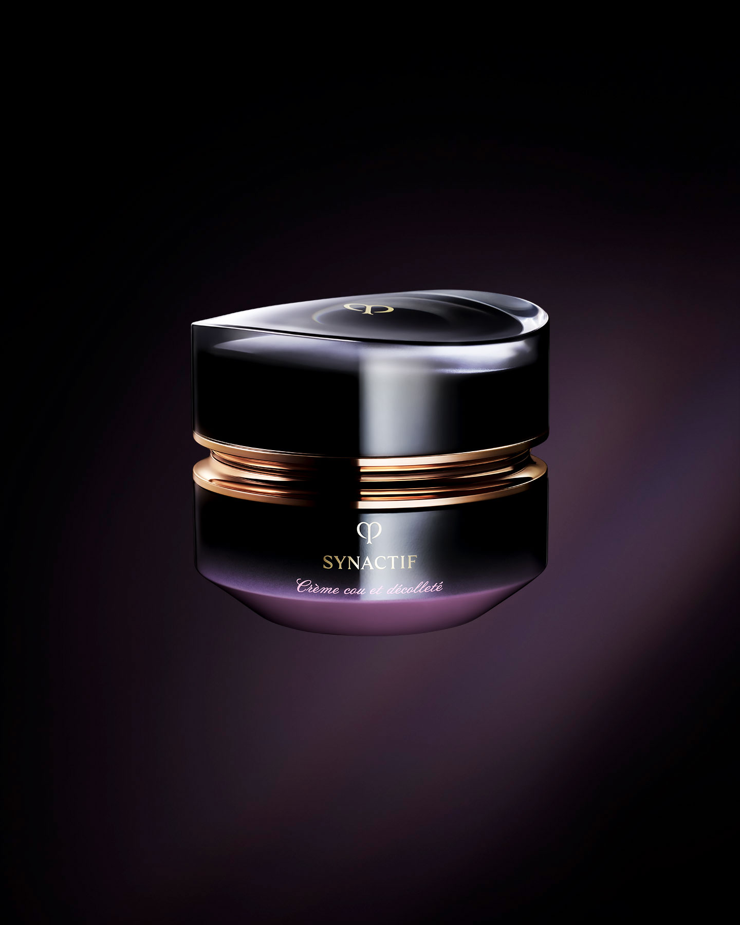 Photo of the Cl&eacute; de Peau Beaut&eacute; Synactif NECK & D&Eacute;COLLET&Eacute; CREAM. The cream is presented in a jar with a black-to-purple gradient. The lid features a sculptural gold design, and the 'SYNACTIF' logo is elegantly displayed on the front.