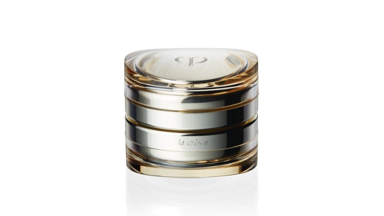 Photo of a luxurious glass container with a layered design of gold and silver tones. The front is engraved with the text &ldquo;la cr&egrave;me,&rdquo; and the brand logo is embossed on the top (former packaging).