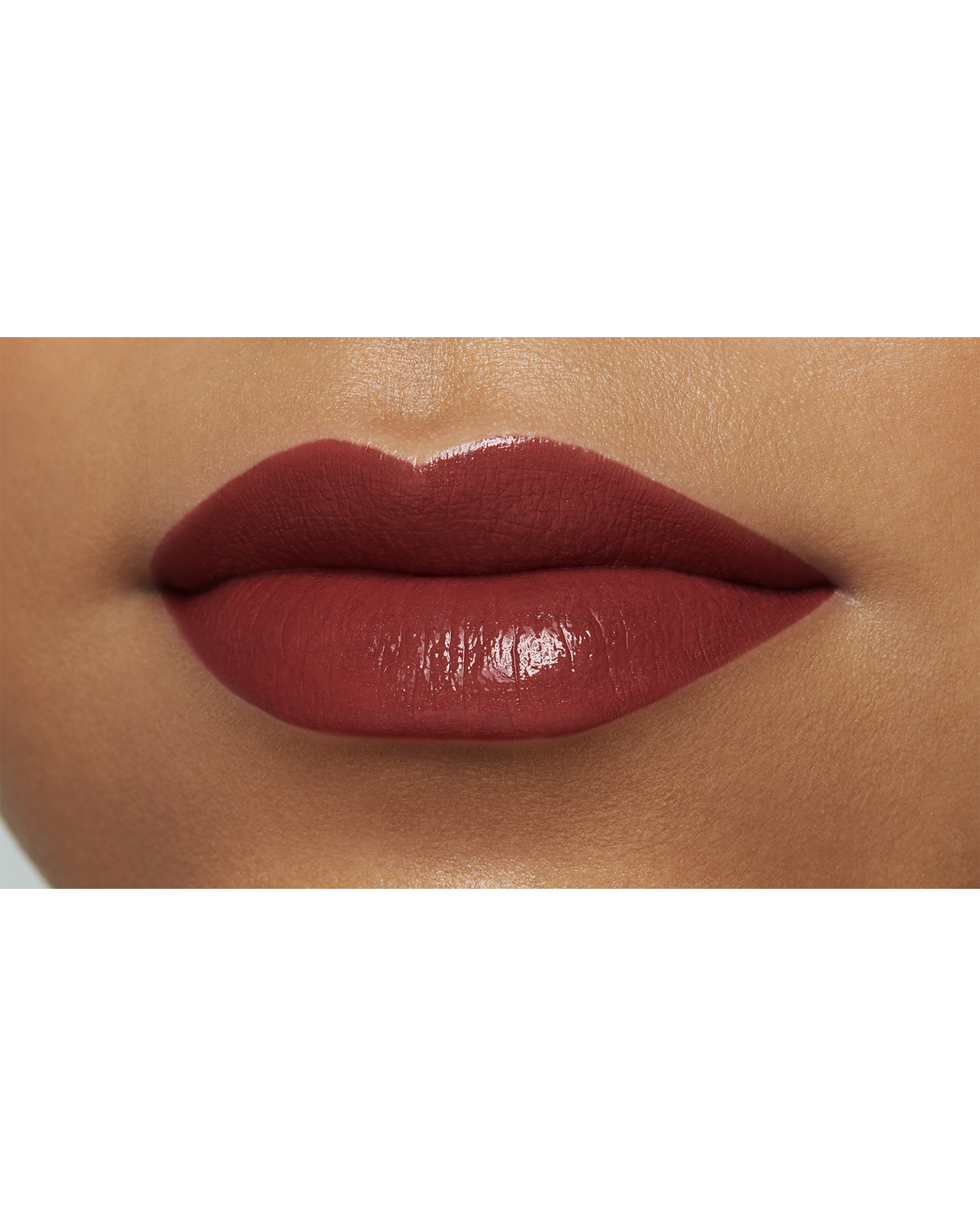 Photo of the lips of a model with a deep skin tone wearing "LIPSTICK" in the shade Beguiling Brick.