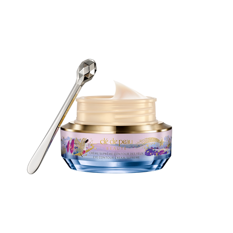 Photo of the 26 AW Holiday Collection limited-edition EYE CONTOUR CREAM SUPREME. The jar is open,revealing the smooth pale cream inside, alongside a faceted silver spatula.