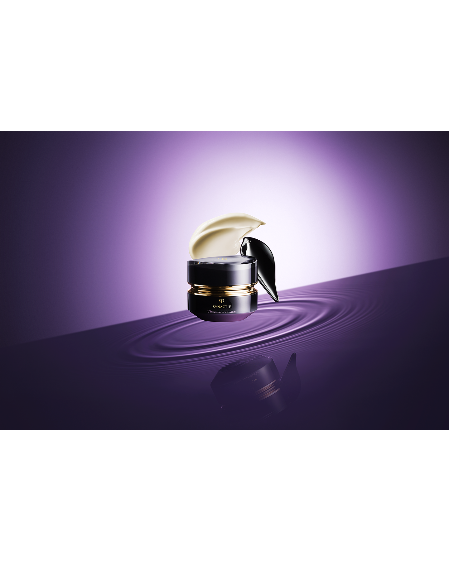 Photo of the black-themed "SYNCACTIF NECK & D&Eacute;COLLET&Eacute; CREAM jar is placed on a purple water surface, showcasing the creamy texture and the appearance of the cream being scooped up with a spatula.