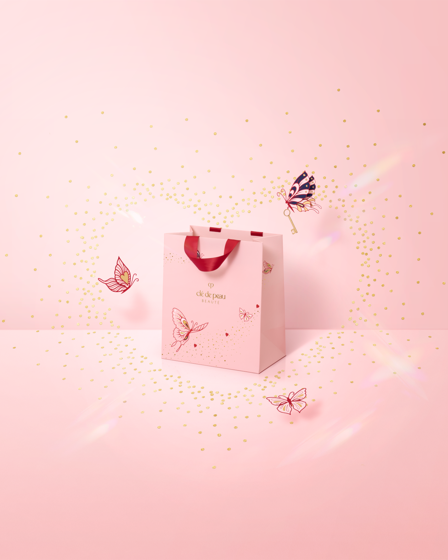 Photo of the 26 SS Collection limited-edition shopping bag. The pale pink bag with red ribbon handles features butterfly illustrations and sparkling gold accents, embodying the Unlock Your Heart theme. 