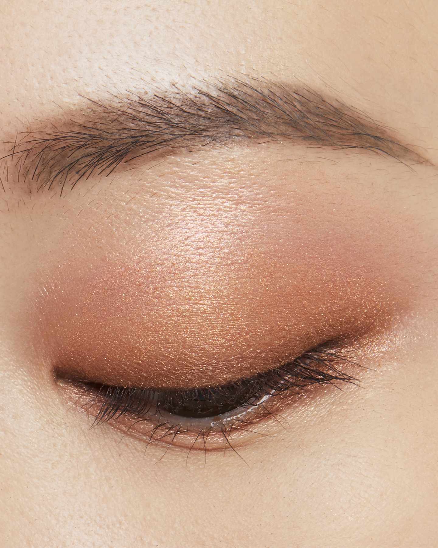 Photo of a medium skin tone model wearing EYE COLOR QUAD in 13-Sunwarmed Stonest on the eyes.