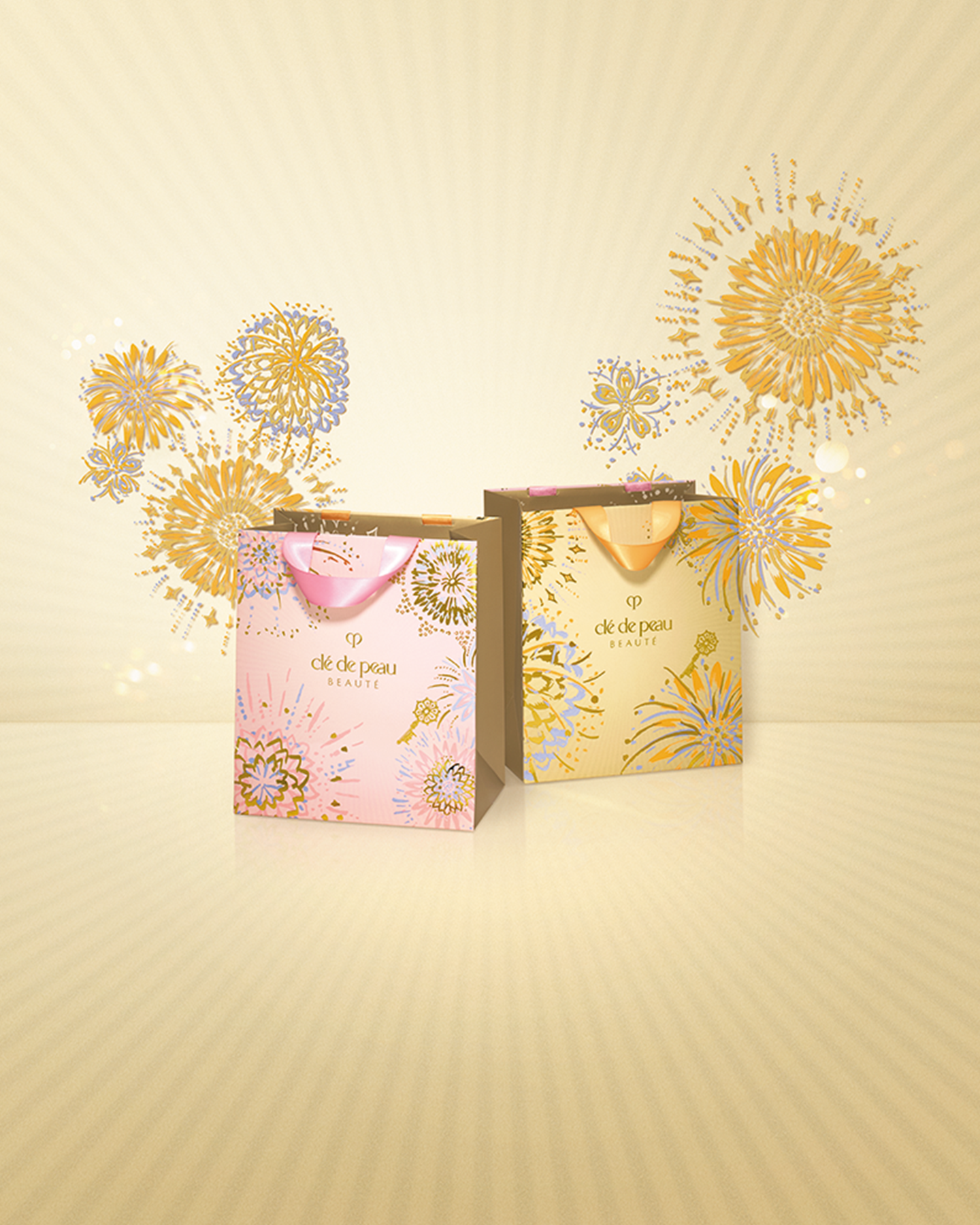 Photo of the 26 SS Gift Collection limited-edition shopping bags. Two bags&mdash;one pink and one golden-toned&mdash;feature the Radiance Fireworks design with flowers blooming like fireworks.