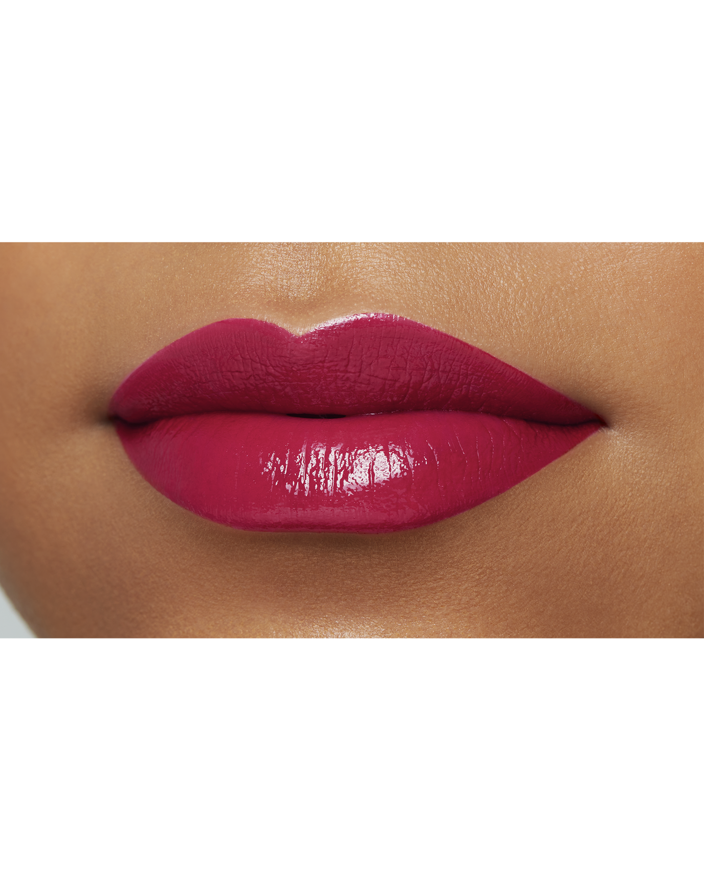 Photo of the lips of a model with a deep skin tone wearing "LIPSTICK" in the shade Raspberry Radiance.
