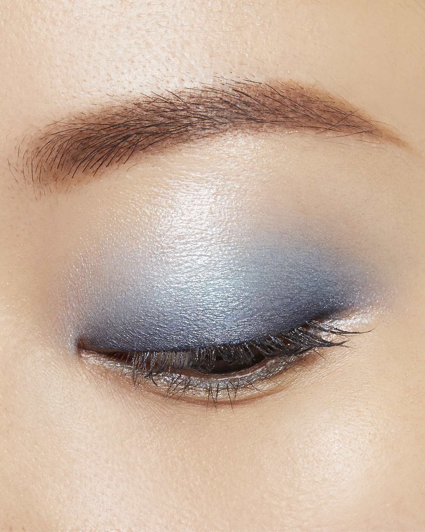 Photo of a medium skin tone model wearing EYE COLOR QUAD in 11-Azure Blue Seat on the eyes.